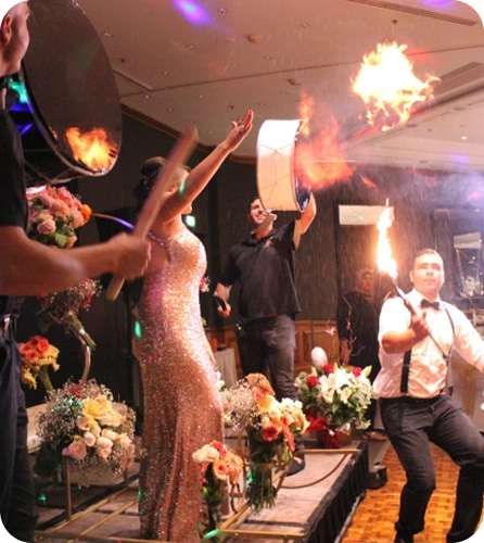 A dynamic, high-energy performance at what looks like a formal event, possibly a wedding reception or gala, with music and fire effects.